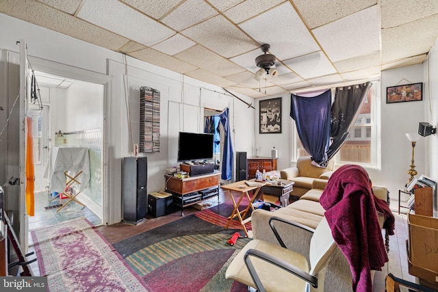 living area with a healthy amount of sunlight, a drop ceiling, and ceiling fan