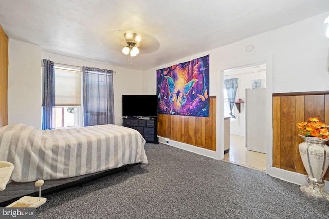 bedroom with ceiling fan, a wainscoted wall, carpet floors, and wood walls