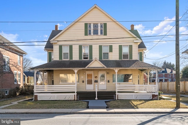 view of front of home with covered porch, roof with shingles, and fence