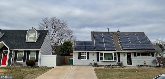 view of front facade with solar panels, a front lawn, and fence