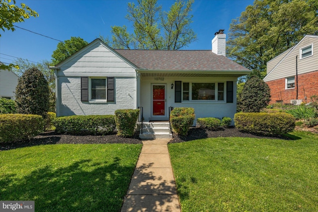 bungalow featuring a shingled roof, a front lawn, and a chimney
