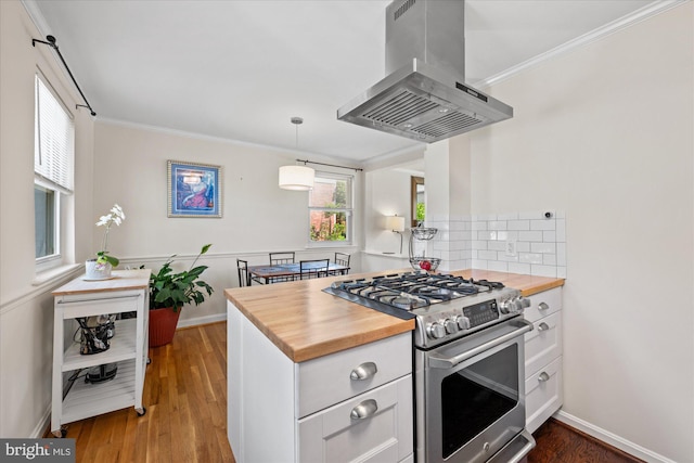 kitchen with stainless steel gas range, crown molding, white cabinetry, island exhaust hood, and butcher block counters