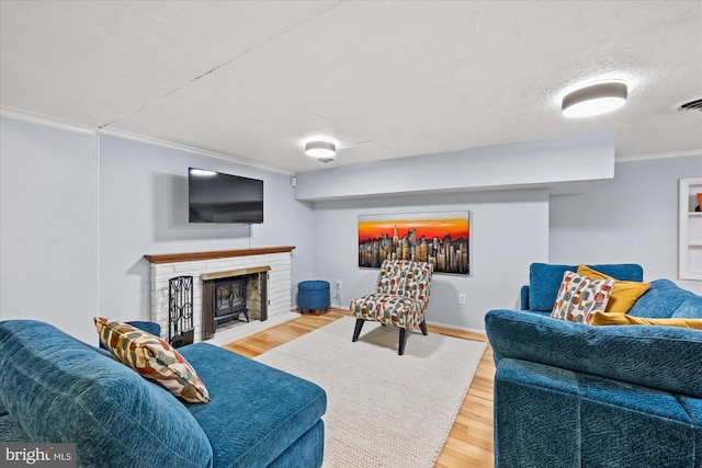 living area featuring crown molding, a brick fireplace, and wood finished floors