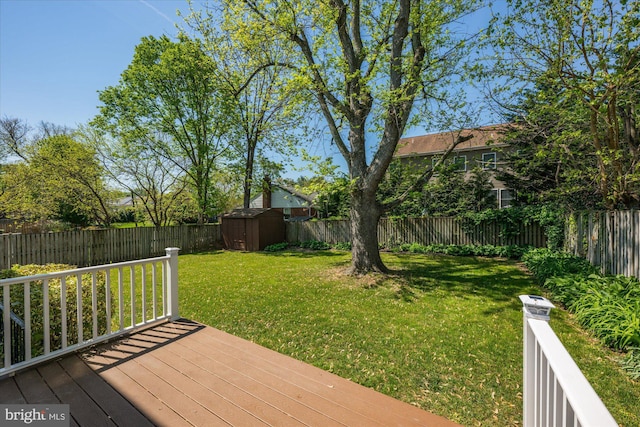 wooden deck featuring a lawn, a storage unit, an outbuilding, and a fenced backyard
