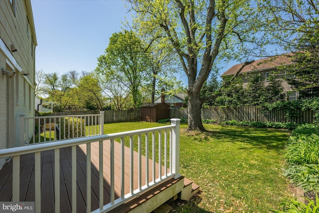 view of yard with an outbuilding, a shed, a fenced backyard, and a wooden deck