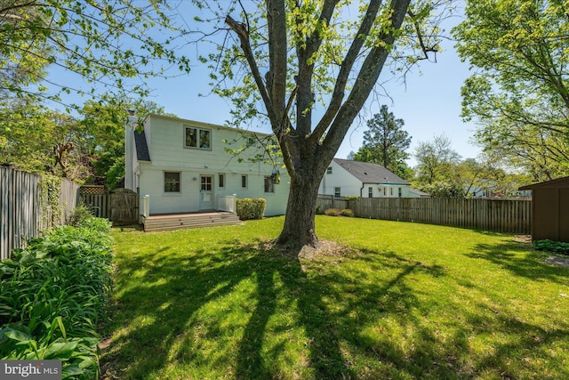 back of house featuring a lawn, a fenced backyard, a wooden deck, and a chimney