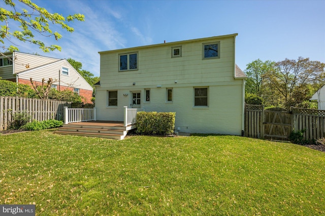 rear view of house with a lawn, a deck, a gate, and a fenced backyard