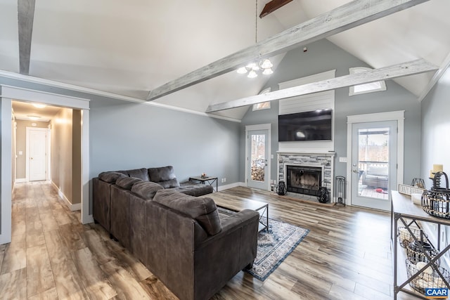 living room with baseboards, a tile fireplace, lofted ceiling with beams, wood finished floors, and a chandelier