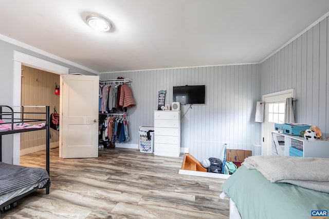 bedroom with crown molding, a closet, baseboards, and wood finished floors