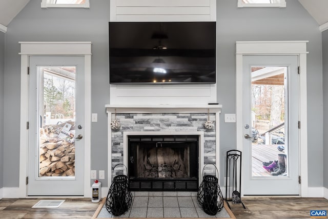 living area featuring a tile fireplace, visible vents, and wood finished floors