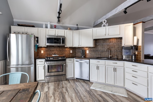 kitchen featuring appliances with stainless steel finishes, a sink, white cabinetry, and decorative backsplash