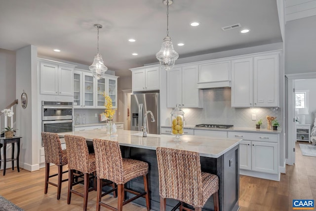 kitchen featuring stainless steel appliances, light wood-style flooring, visible vents, and white cabinetry