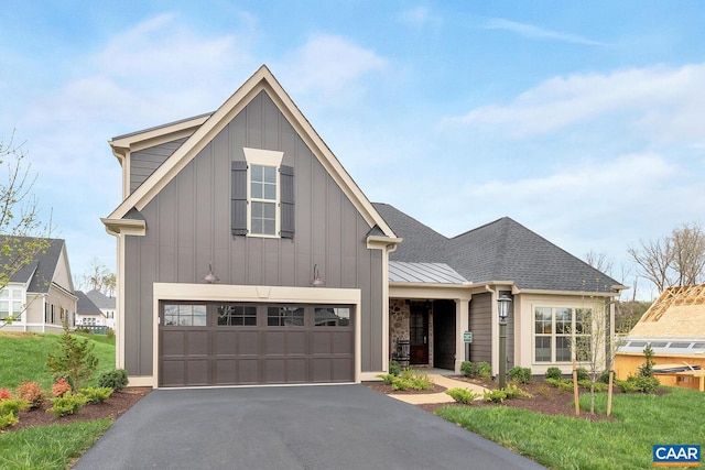 modern farmhouse style home with roof with shingles, an attached garage, board and batten siding, a standing seam roof, and driveway