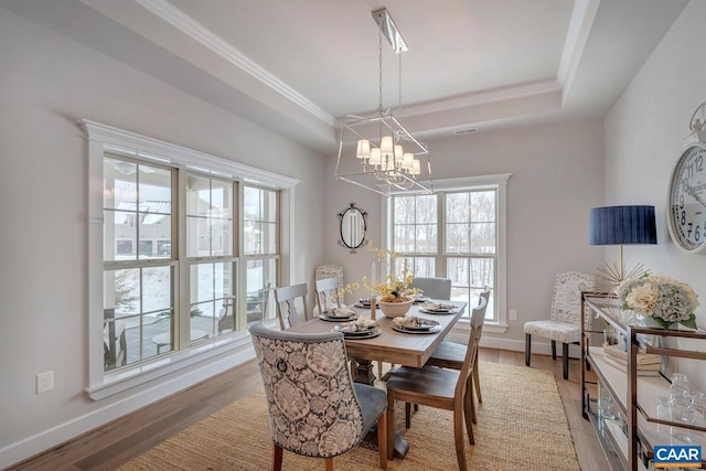 dining space featuring a tray ceiling, a notable chandelier, light wood-style flooring, and baseboards