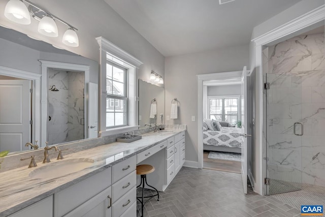 ensuite bathroom featuring double vanity, a sink, and a marble finish shower