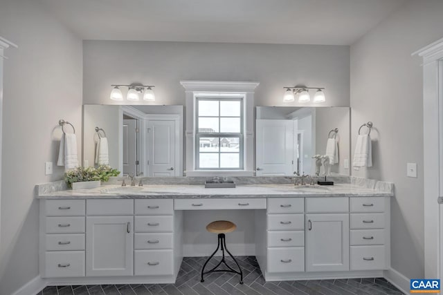 bathroom featuring a sink, baseboards, and double vanity