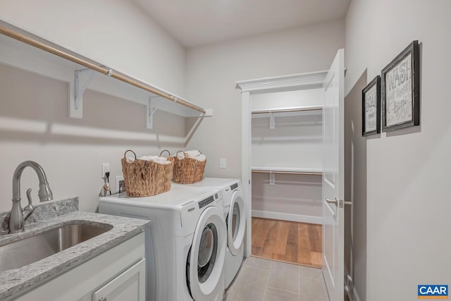 clothes washing area featuring laundry area, light tile patterned floors, washer and clothes dryer, and a sink