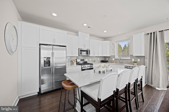 kitchen with visible vents, stainless steel appliances, a kitchen bar, and a sink