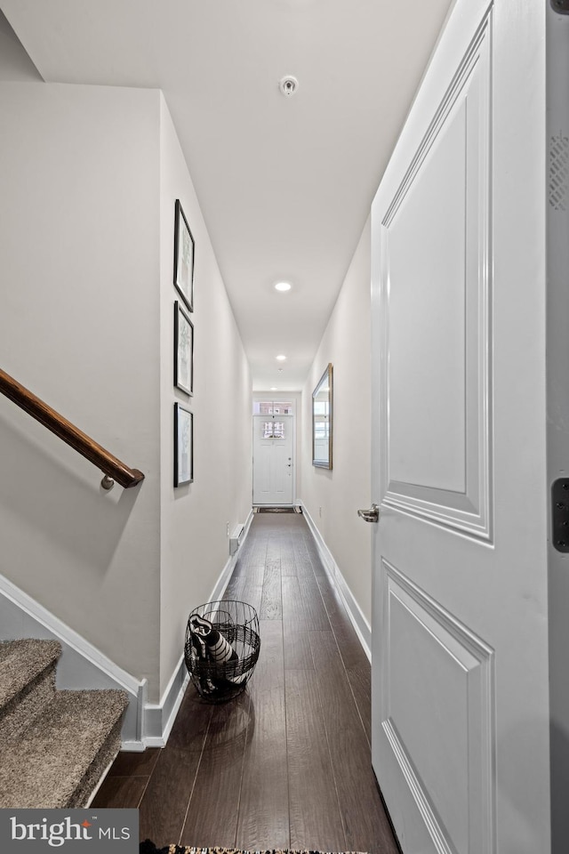 hallway with dark wood-style floors, stairway, and baseboards