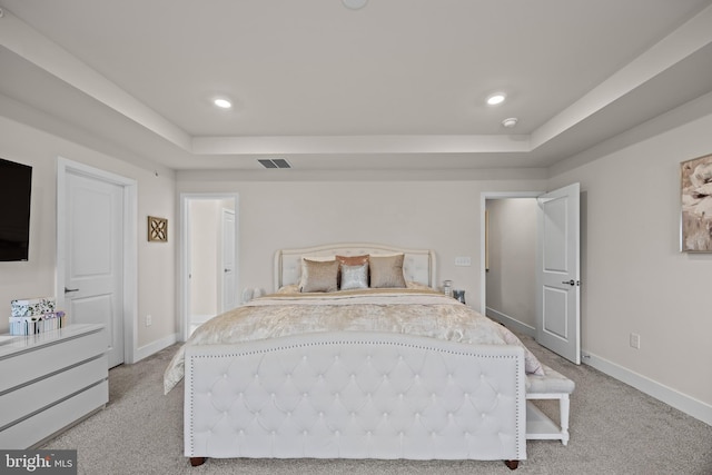 bedroom featuring a raised ceiling, baseboards, visible vents, and light carpet