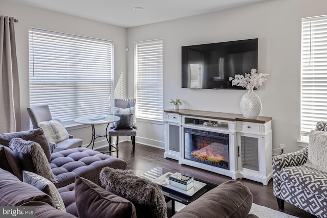 living room with a glass covered fireplace, wood finished floors, and baseboards