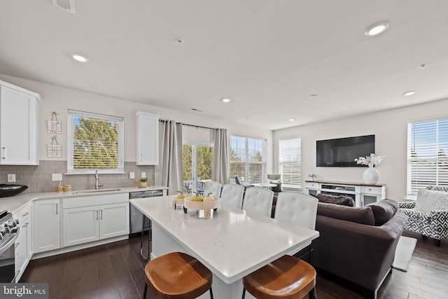 kitchen featuring a breakfast bar, dark wood-style flooring, a sink, appliances with stainless steel finishes, and open floor plan