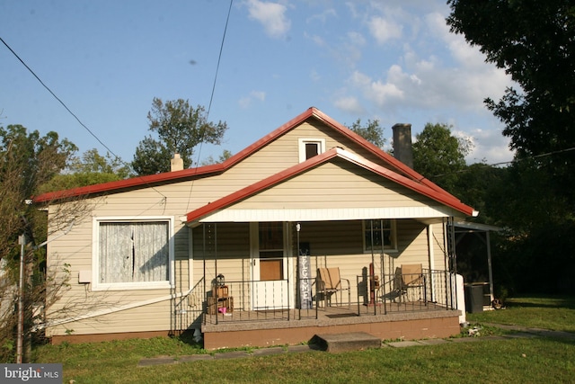 rear view of property with covered porch and a yard