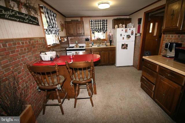 kitchen featuring white appliances, plenty of natural light, crown molding, and a sink