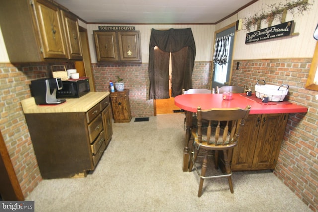 kitchen featuring black microwave, light carpet, and brick wall