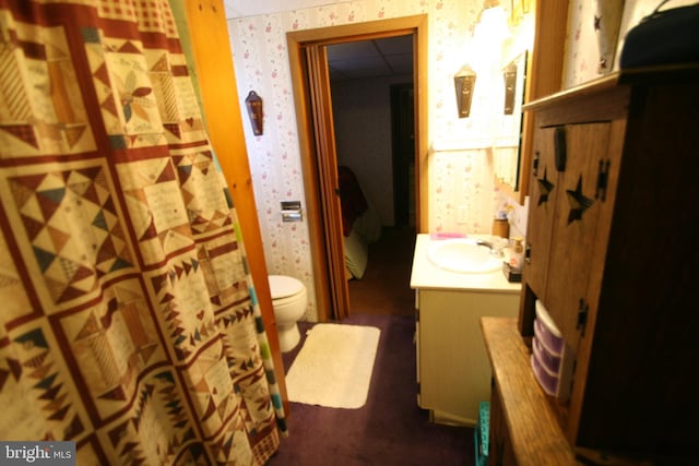 full bath with toilet, a shower with curtain, vanity, and wallpapered walls