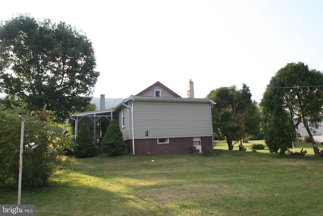 view of side of home with a chimney and a lawn