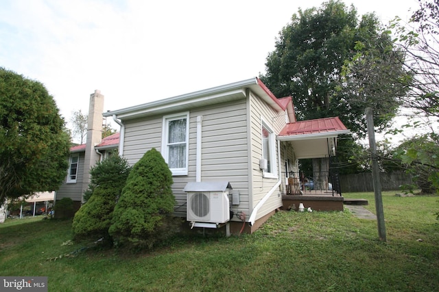 view of property exterior with ac unit, a chimney, metal roof, and a lawn