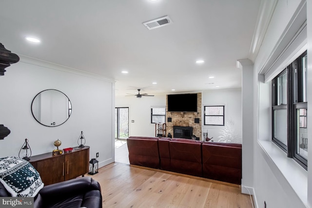 interior space featuring visible vents, light wood-style flooring, recessed lighting, a large fireplace, and crown molding