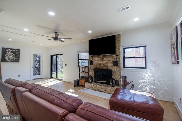 living room featuring plenty of natural light, light wood-style floors, visible vents, and ornamental molding