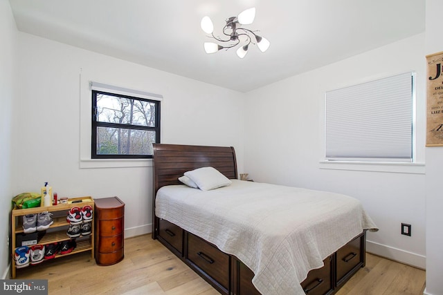 bedroom featuring an inviting chandelier, light wood-style flooring, and baseboards