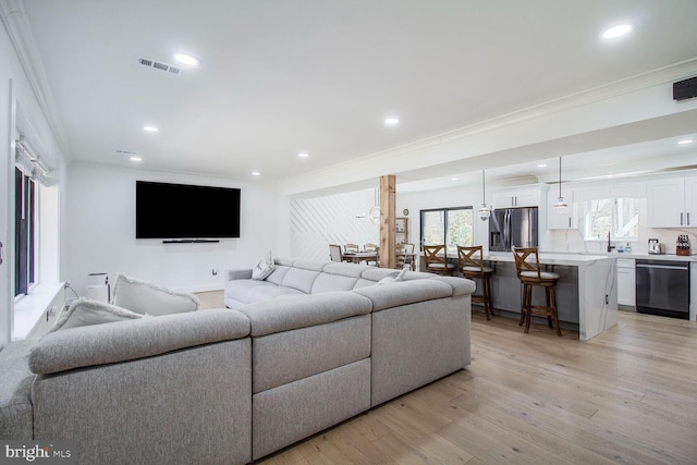 living room featuring recessed lighting, visible vents, crown molding, and light wood finished floors