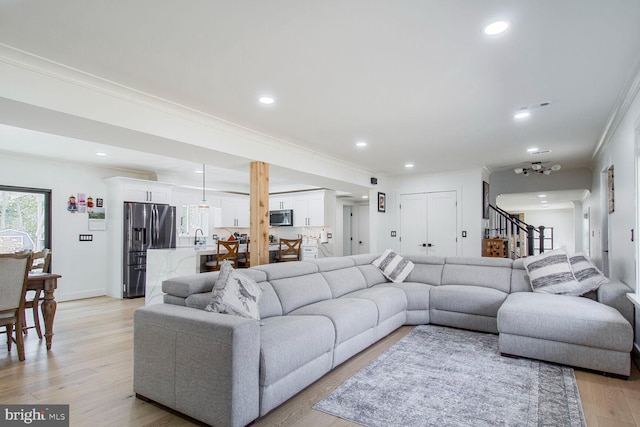 living area featuring recessed lighting, light wood-style flooring, ornamental molding, and stairs