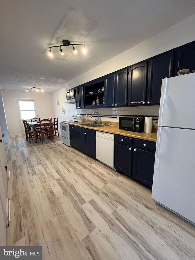 kitchen featuring white appliances, a sink, light countertops, light wood-type flooring, and backsplash