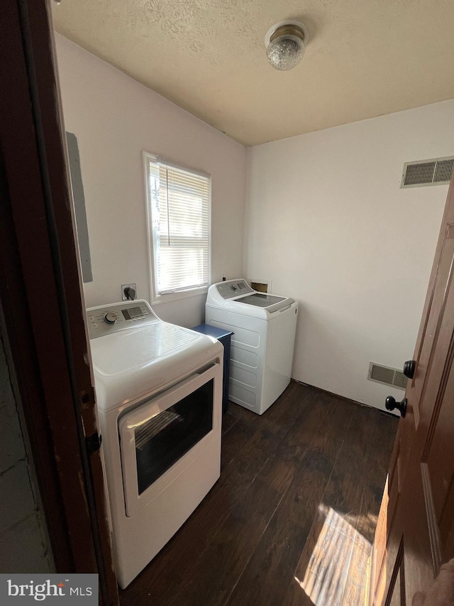 laundry area featuring dark wood-type flooring, washing machine and dryer, laundry area, and visible vents