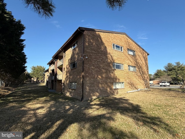 view of side of property featuring a lawn and brick siding