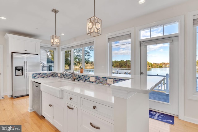 kitchen featuring dishwasher, light countertops, fridge with ice dispenser, and a sink