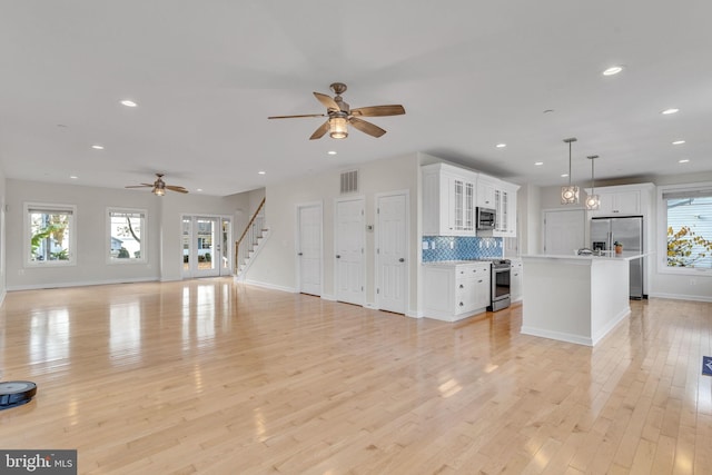 kitchen featuring light wood finished floors, plenty of natural light, visible vents, appliances with stainless steel finishes, and open floor plan