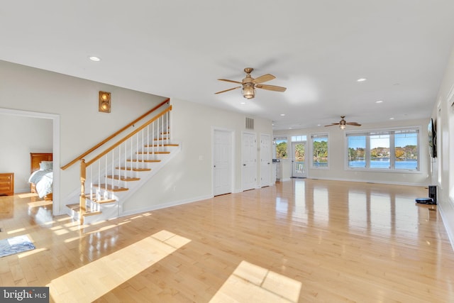 unfurnished living room featuring recessed lighting, visible vents, light wood-style flooring, baseboards, and stairs