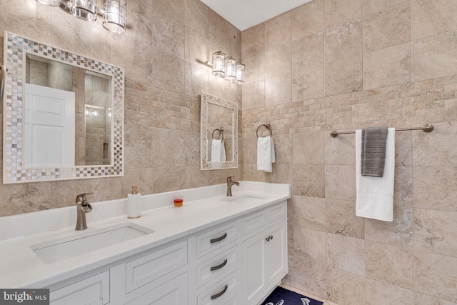 full bath featuring double vanity, tile walls, and a sink