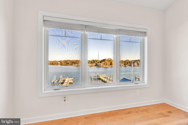 interior space featuring a water view, light wood-type flooring, and baseboards