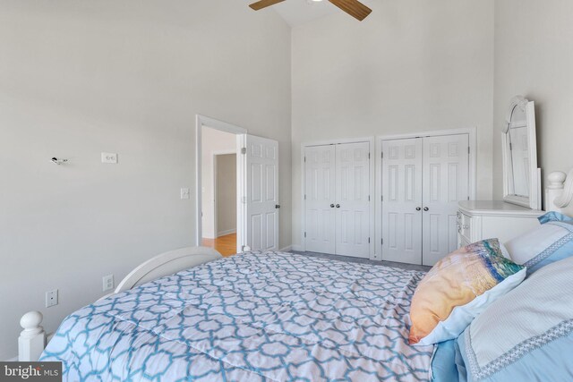 bedroom with baseboards, two closets, a towering ceiling, and a ceiling fan