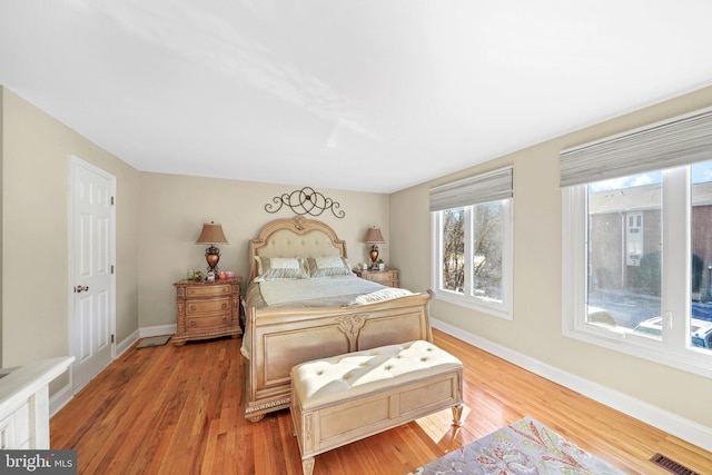 bedroom featuring light wood-style floors, visible vents, and baseboards