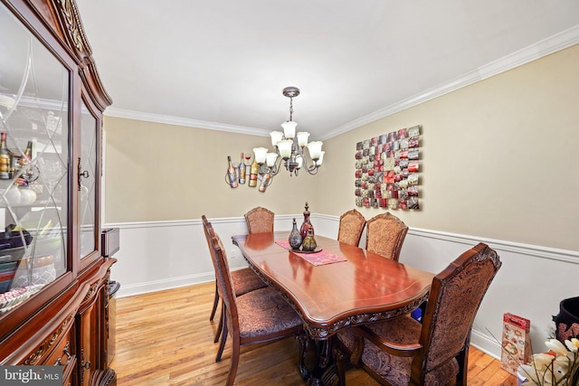 dining area with baseboards, a notable chandelier, crown molding, and light wood finished floors