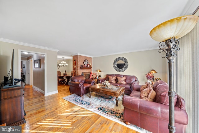 living area with an inviting chandelier, crown molding, baseboards, and wood finished floors