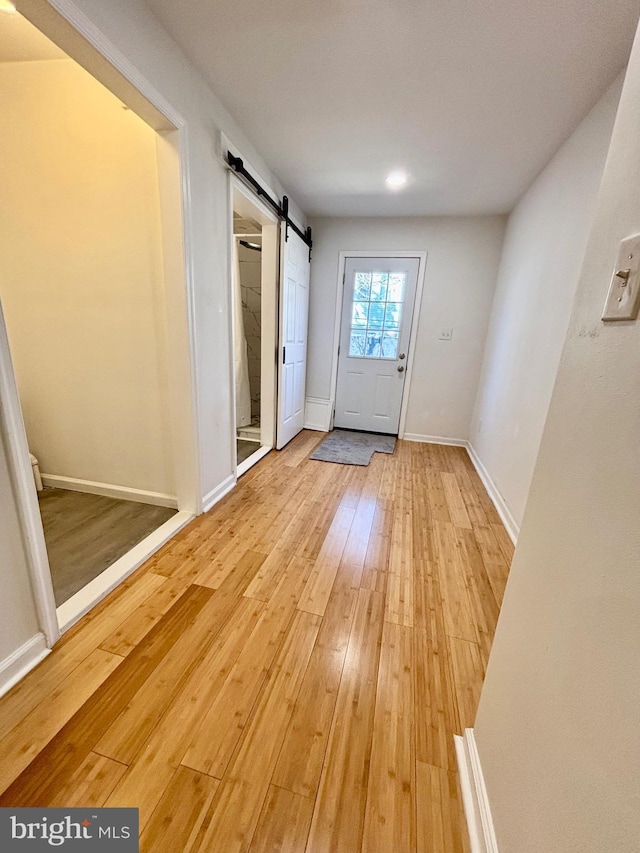 entryway featuring light wood-style floors, baseboards, and a barn door